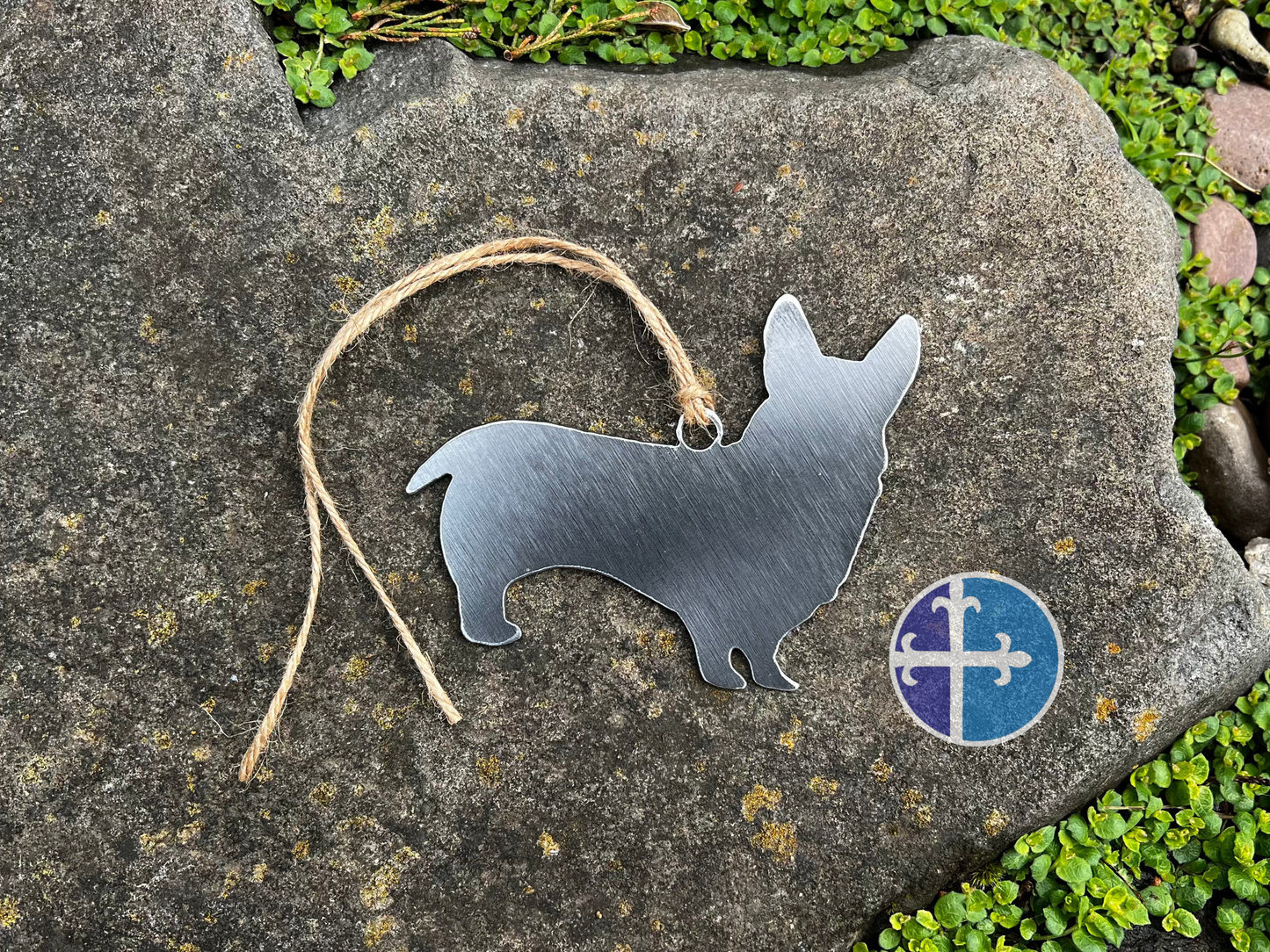 Corgi dog-shaped metal ornament with hanging twine displayed outdoors.