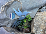 Load image into Gallery viewer, Steel bird ornament featuring a heart-shaped cutout, placed on rocks with small clover leaves.
