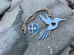 Load image into Gallery viewer, Rustic steel hummingbird decoration, laying on gray stone, showing heart detail.
