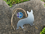 Load image into Gallery viewer, Backside view of brushed steel Corgi ornament on textured stone.
