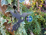 Load image into Gallery viewer, Hummingbird-shaped metal ornament with a rustic finish, displayed on ivy-covered wood.
