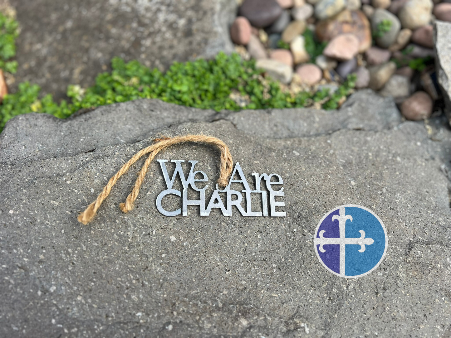 Decorative sign with 'We Are CHARLIE' text and a blue logo on a stone surface.