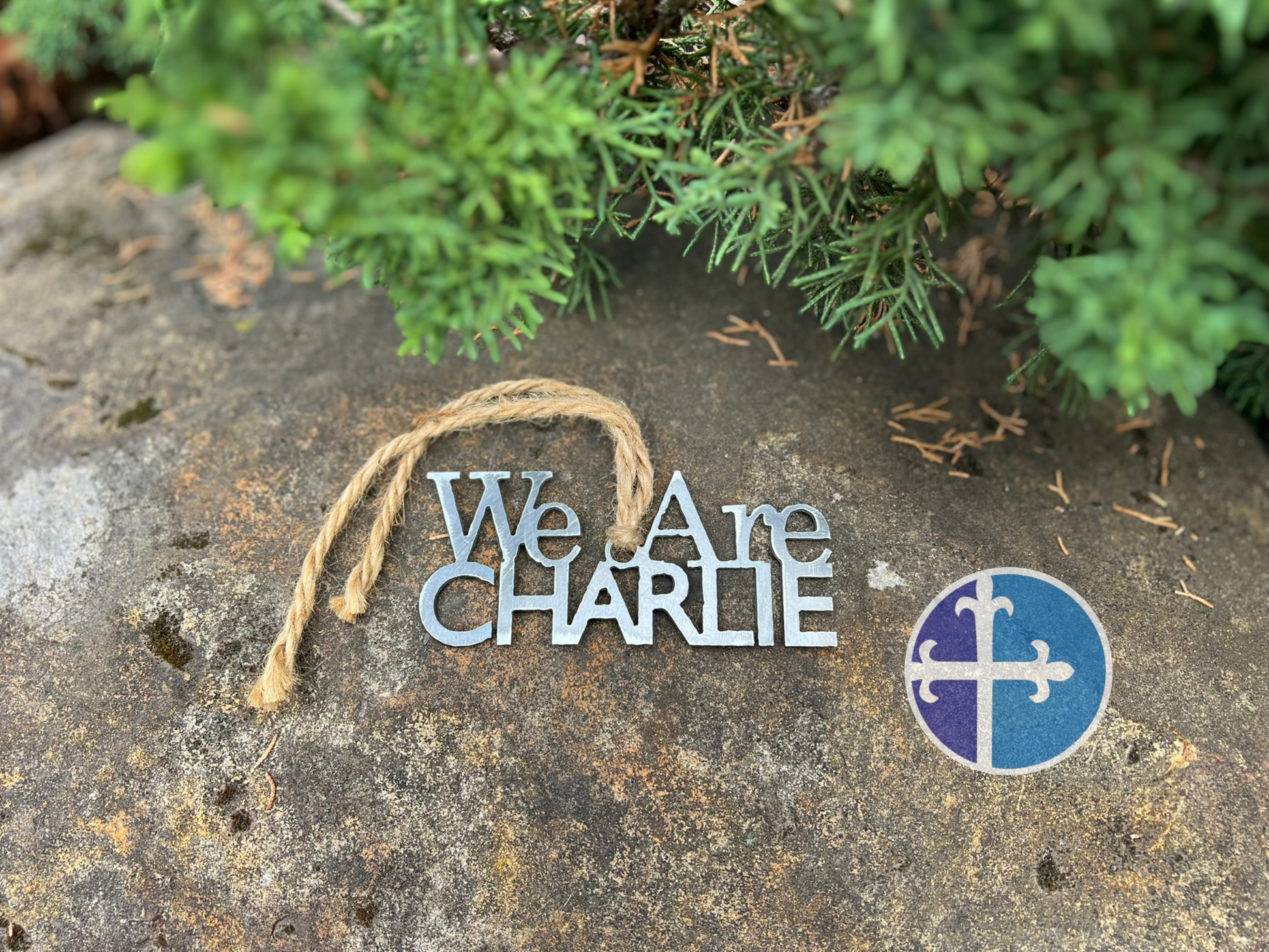 Close-up of metal “We Are Charlie” ornament honoring Charlie Kirk, on rock background.