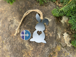 Load image into Gallery viewer, Overhead view of a steel bunny silhouette ornament with a heart cutout, displayed on a stone surface with greenery in the background.
