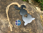Load image into Gallery viewer, Rustic steel bunny ornament with a heart cutout, shown lying on a stone surface with natural jute twine for hanging.
