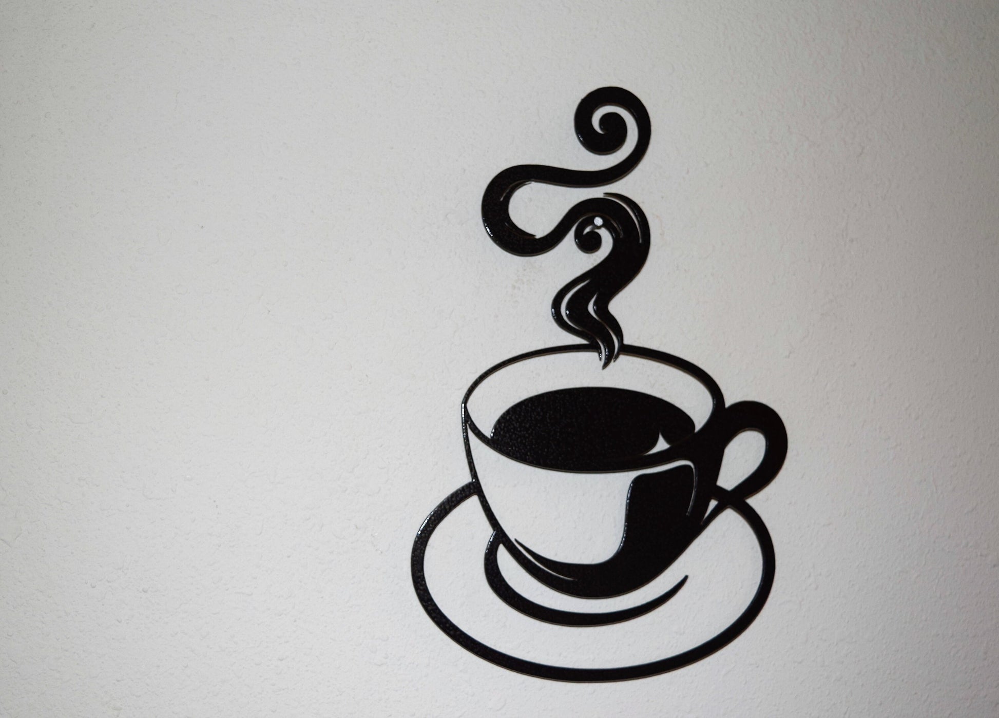 Enhance your outdoor space with a hammered black steel cutout of a steaming coffee cup, adding rustic charm to your decor