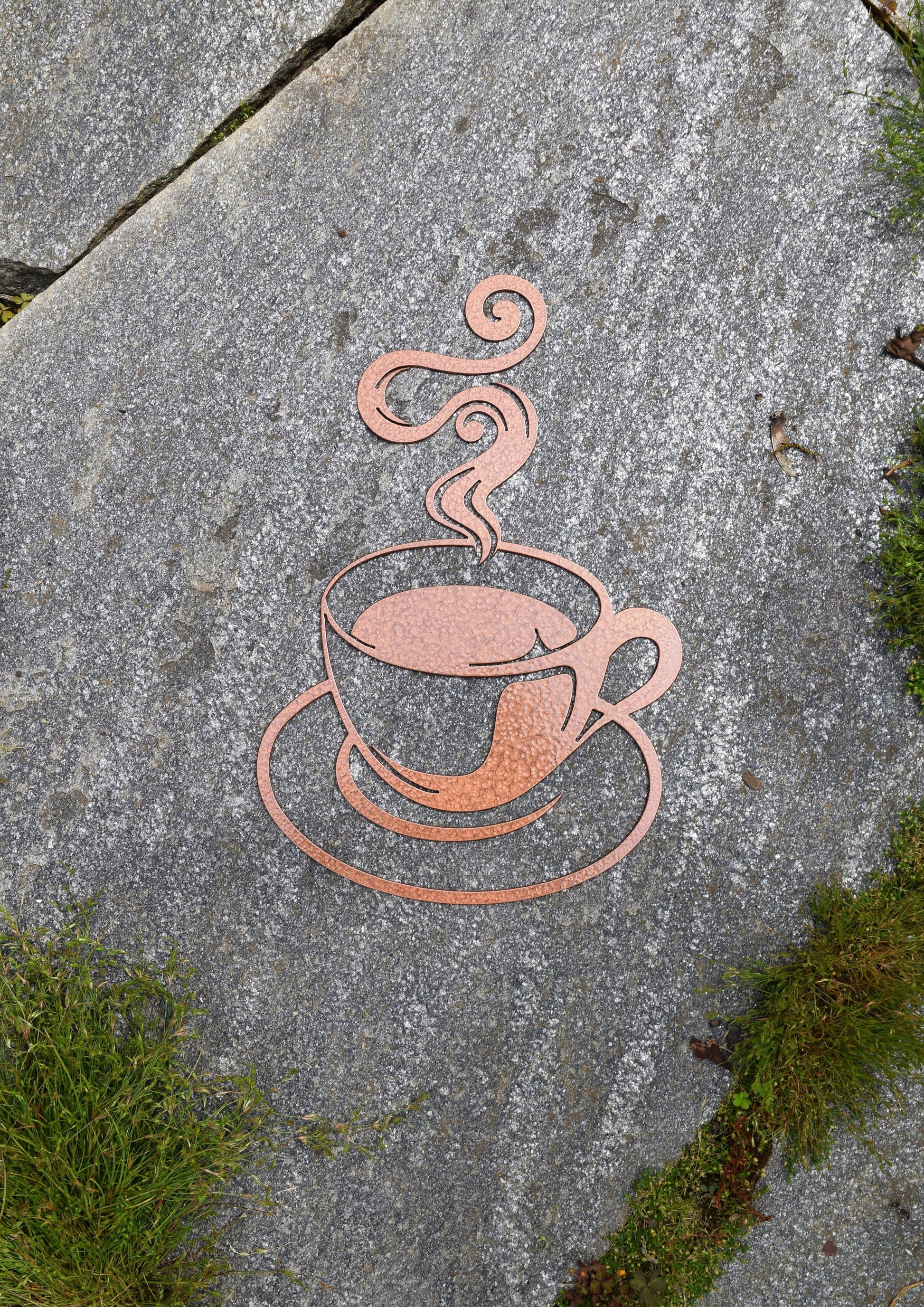 Enhance your home decor with a captivating hammered copper-painted steel cutout of a steaming coffee cup. This unique coffee-themed art piece adds warmth and sophistication to any room, making it a must-have for coffee lovers and interior design enthusiasts alike.